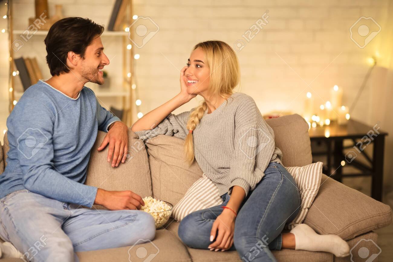 Loving Couple Talking And Eating Popcorn In Living Room